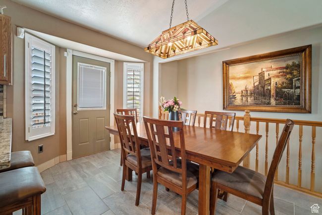 Dining room featuring a textured ceiling, plenty of natural light, a notable chandelier, and baseboards | Image 5