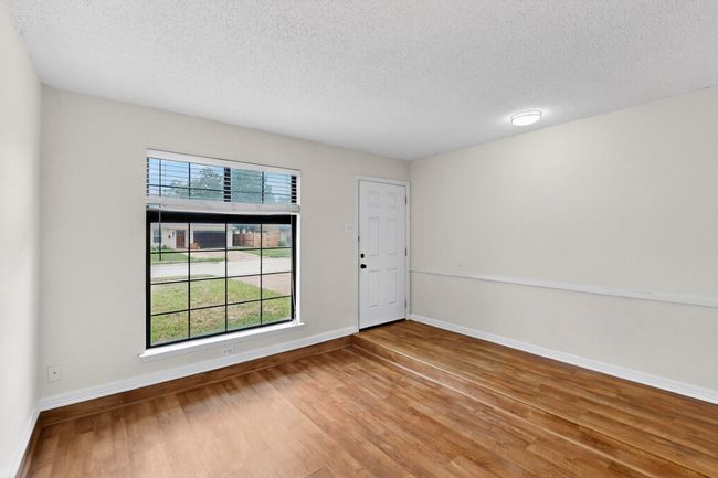 Living area with wood finished floors and a textured ceiling | Image 4