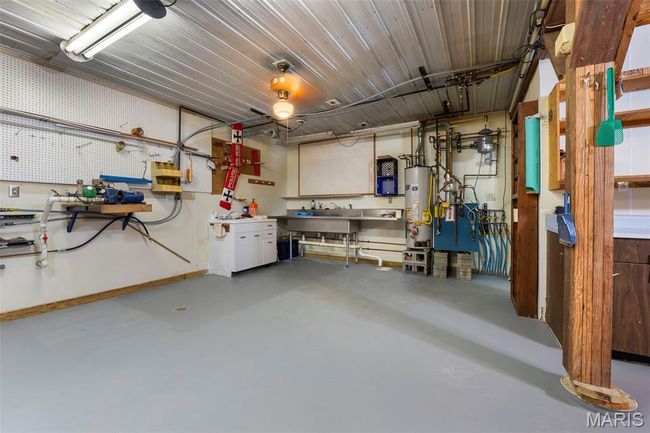 Garage with a workshop area and gas water heater | Image 33