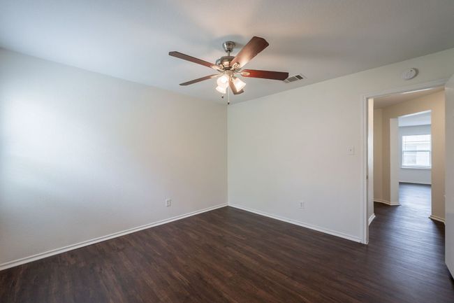 Empty room featuring dark wood-style flooring, ceiling fan, baseboards, and a smoke detector | Image 24