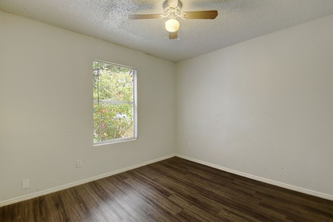 Empty room with dark wood finished floors, baseboards, ceiling fan, and a textured ceiling | Image 18
