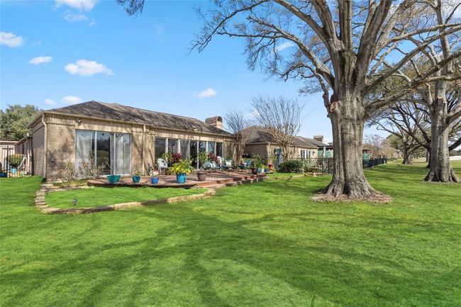 The beautifully landscaped backyard features a spacious wooden deck overlooking the lush green fairways. Mature trees provide shade and enhance the serene atmosphere, while the well-maintained lawn and garden beds add to the home's curb appeal. A perfect blend of indoor-outdoor living with picturesque golf course views. | Image 37