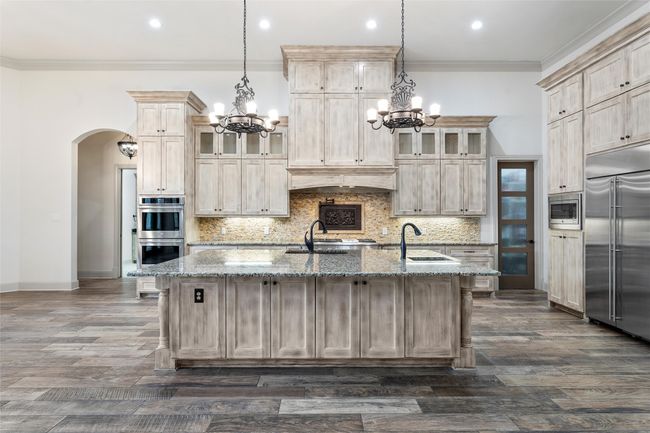 Kitchen featuring built in appliances, a notable chandelier, ornamental molding, and a sink | Image 12