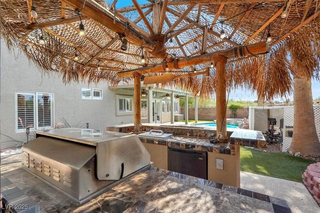 Fenced backyard with an outdoor kitchen, ceiling fan, and a gazebo | Image 44