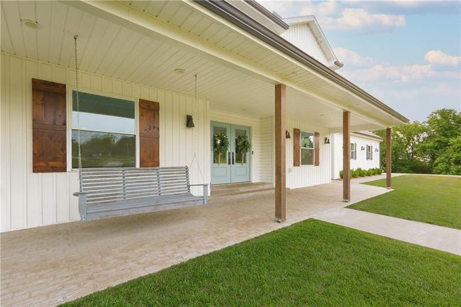 Modern inspired farmhouse featuring driveway, covered porch, a front lawn, a shingled roof, and metal roof | Image 7