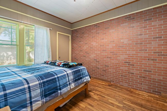 Bedroom featuring brick wall, wood finished floors, and crown molding | Image 17