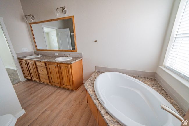 Bathroom featuring a bath, double vanity, wood finished floors, and a sink | Image 30