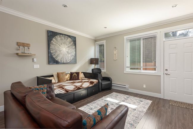 Living room featuring a baseboard radiator, healthy amount of natural light, ornamental molding, wood finished floors, and baseboards | Image 13