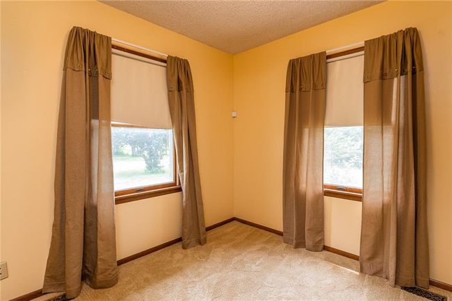 Unfurnished bedroom with multiple windows, light colored carpet, and a textured ceiling | Image 16