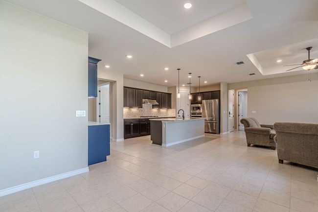 Kitchen with open floor plan, a tray ceiling, decorative backsplash, appliances with stainless steel finishes, and light countertops | Image 19
