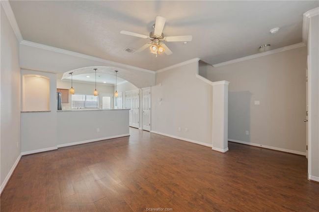 Unfurnished living room with ornamental molding, ceiling fan, baseboards, and dark wood-style flooring | Image 24
