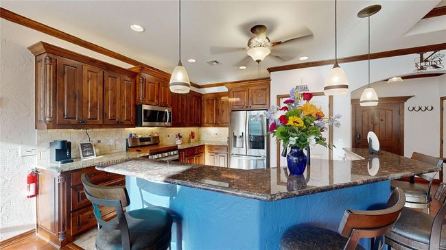 Kitchen featuring ceiling fan, a kitchen bar, backsplash, appliances with stainless steel finishes, and visible vents | Image 18