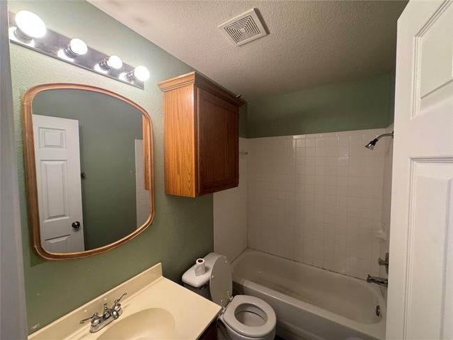 Bathroom with a textured ceiling, vanity, and shower combination | Image 9
