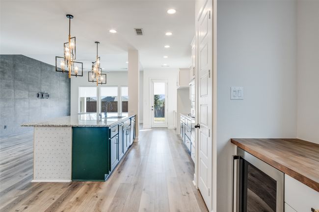 Kitchen featuring wine cooler, light wood-style floors, white cabinets, a chandelier, and recessed lighting | Image 13