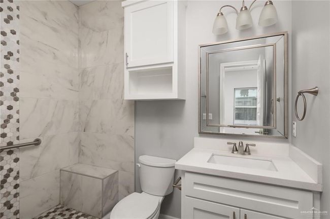 Bathroom featuring toilet, a tile shower, and vanity | Image 7
