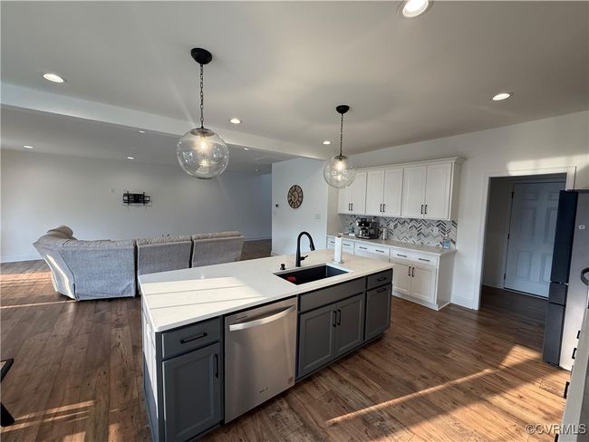 Kitchen with stainless steel dishwasher, a sink, open floor plan, white cabinetry, and light countertops | Image 17