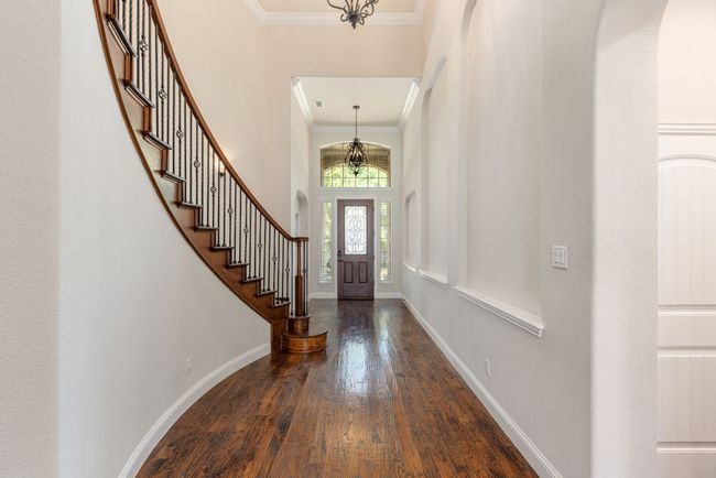 Entrance foyer featuring a notable chandelier, hardwood / wood-style floors, stairs, baseboards, and ornamental molding | Image 14