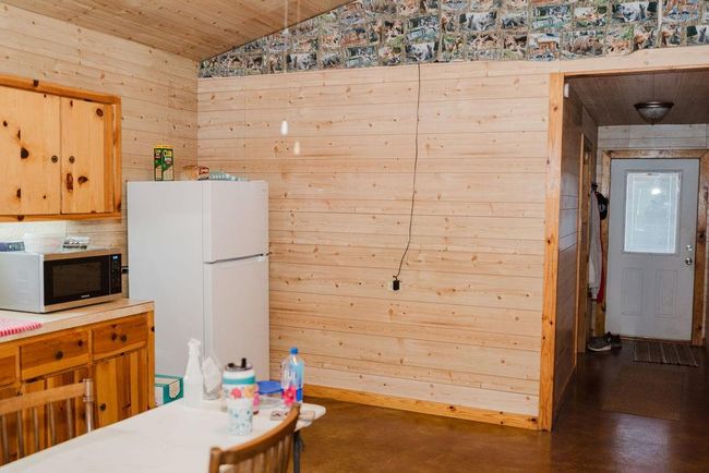 Kitchen featuring freestanding refrigerator, lofted ceiling, wood walls, wood ceiling, and finished concrete flooring | Image 11