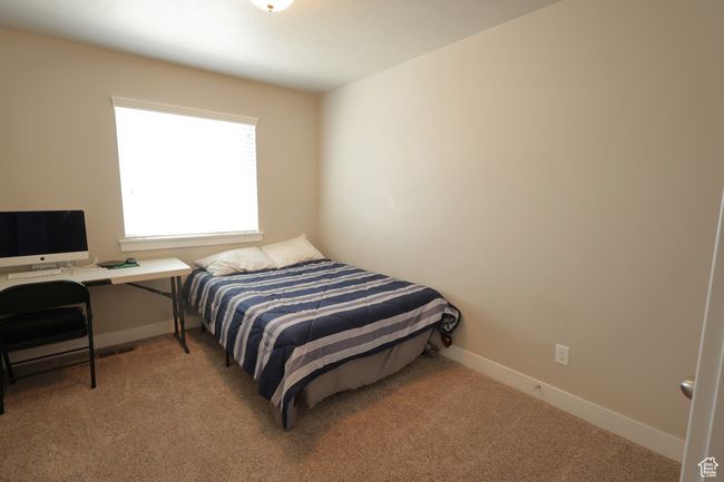 Carpeted bedroom with baseboards and an office area | Image 10