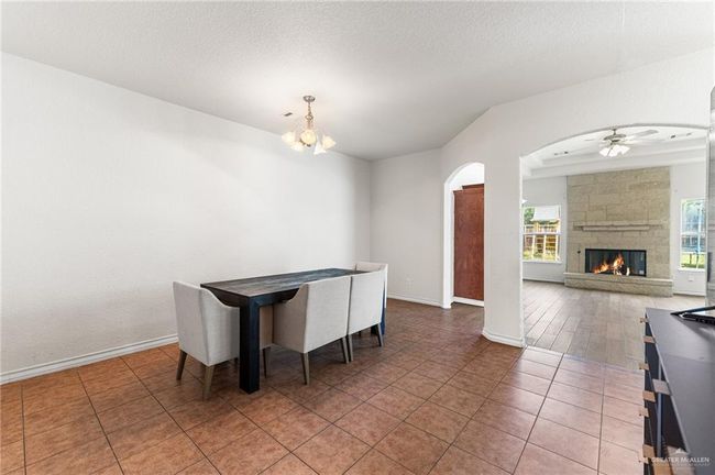 Dining room with a chandelier, ceiling fan, arched walkways, a fireplace, and light tile patterned floors | Image 26