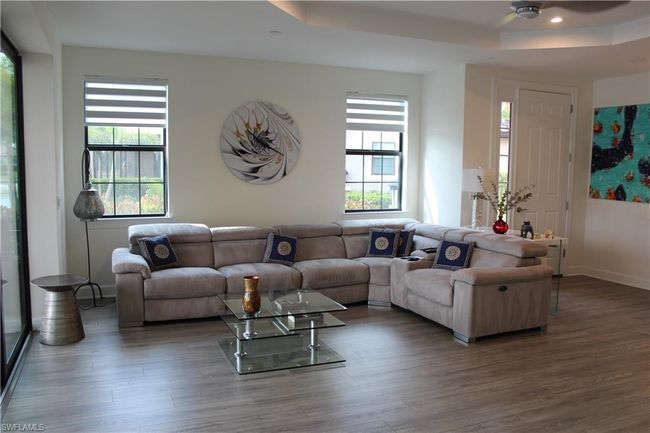 Living room featuring baseboards, ceiling fan, wood finished floors, and a tray ceiling | Image 7