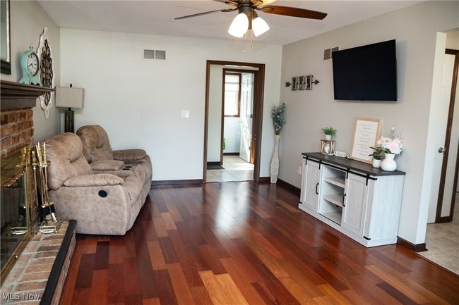 Living area with ceiling fan, a brick fireplace, and dark wood finished floors | Image 25