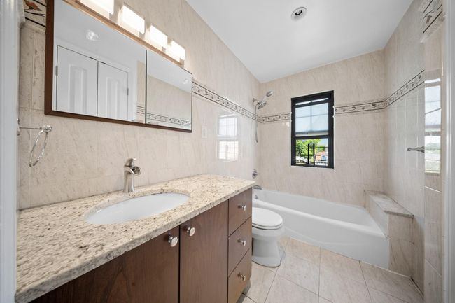Full bathroom with tile walls, vanity, toilet, shower / tub combination, and tile patterned flooring | Image 26