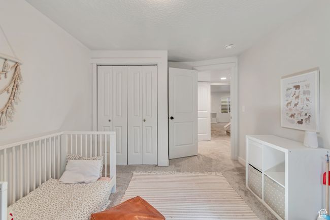 Bedroom featuring light colored carpet, a closet, and a textured ceiling | Image 23