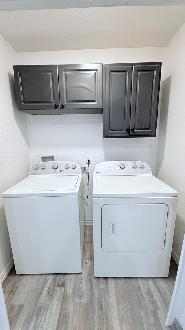 Laundry room featuring cabinet space, separate washer and dryer, light wood-style floors, and baseboards | Image 9