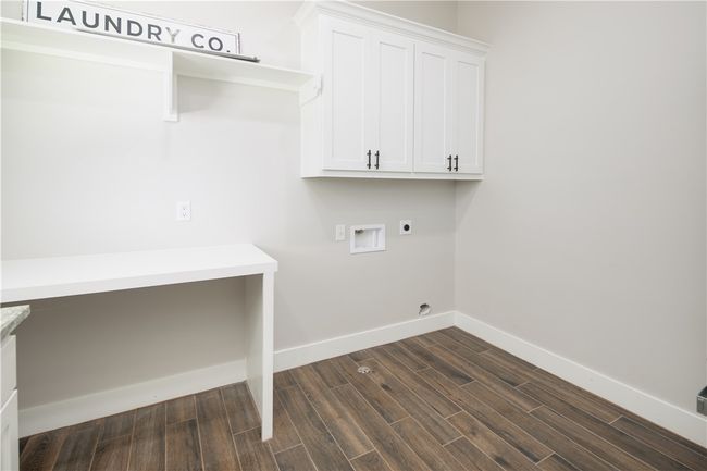 Washroom with cabinet space, hookup for an electric dryer, hookup for a washing machine, and dark wood finished floors | Image 17
