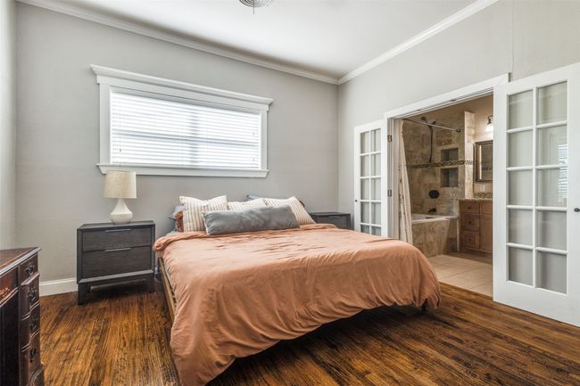 The downstairs primary bedroom suite with large windows, hardwood flooring, and direct access to the en-suite bath is a perfect place to relax. | Image 13