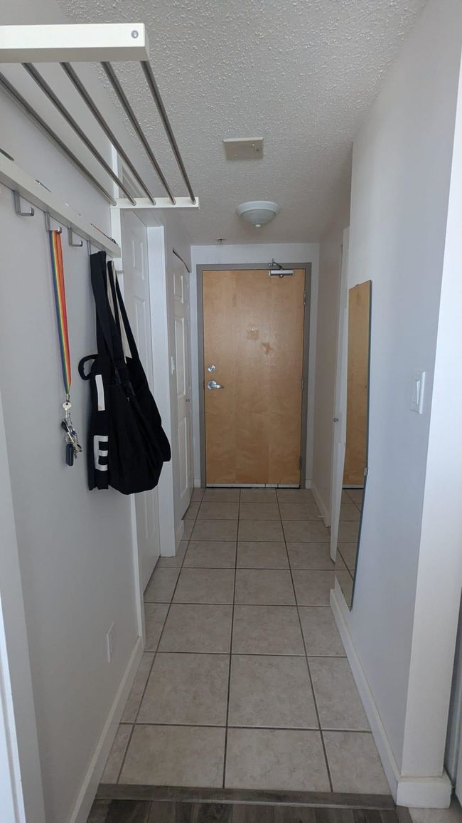 Corridor featuring light tile patterned floors, baseboards, and a textured ceiling | Image 12