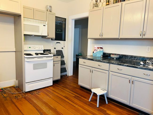 Kitchen featuring dark wood-type flooring and white appliances | Image 7