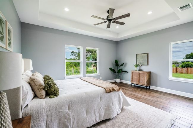 Bedroom featuring a tray ceiling, wood finished floors, multiple windows, baseboards, and recessed lighting | Image 13