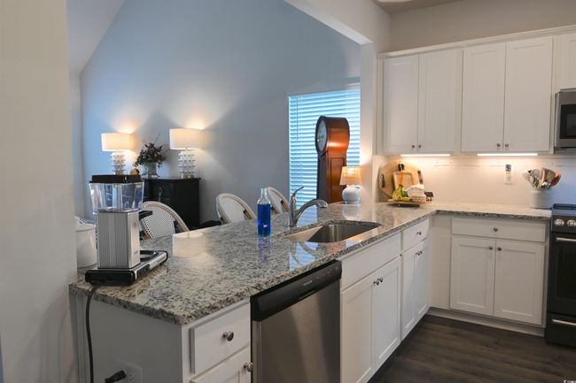 Kitchen featuring stainless steel appliances, white cabinets, a peninsula, and light stone countertops | Image 6
