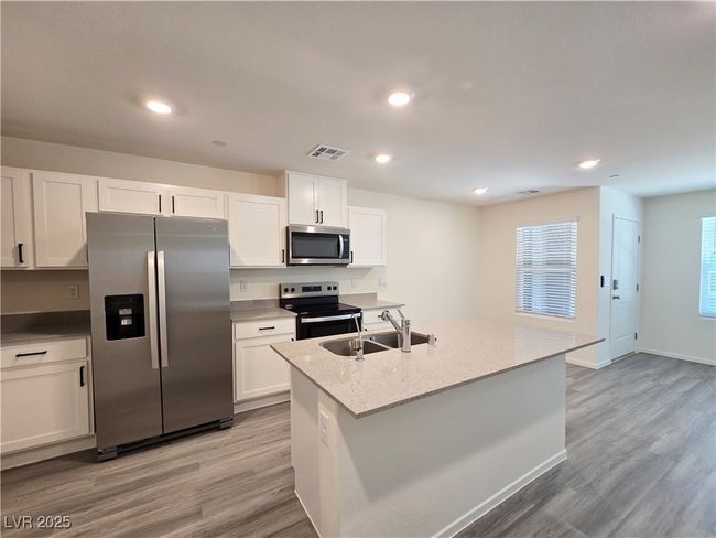 Kitchen featuring appliances with stainless steel finishes, a sink, white cabinets, light wood-style flooring, and recessed lighting | Image 11