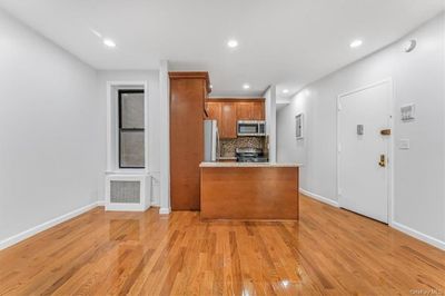 Kitchen featuring radiator, light hardwood / wood-style floors, stainless steel appliances, and decorative backsplash | Image 2