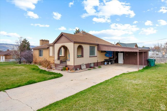 Bungalow-style house featuring driveway, a front yard, roof with shingles, a chimney, and a carport | Image 14