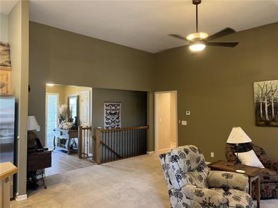 Living area featuring light carpet, a towering ceiling, and ceiling fan | Image 3