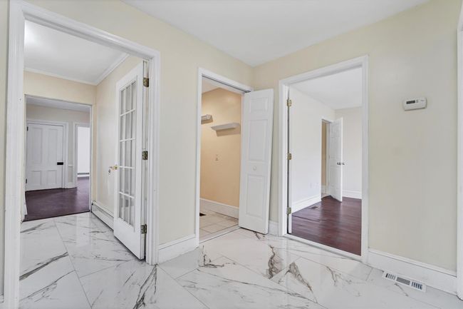 Hall featuring baseboards, baseboard heating, marble look tiles, and ornamental molding | Image 5