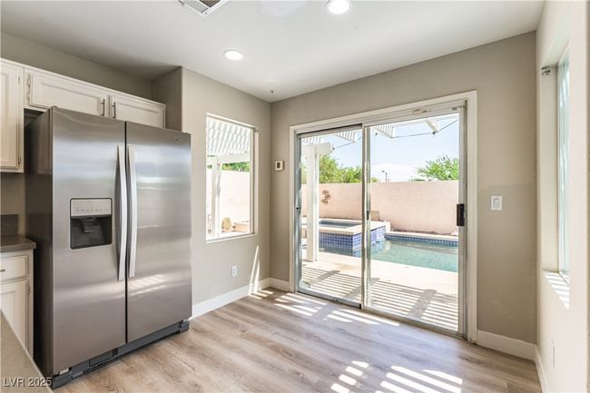 Kitchen with stainless steel fridge, white cabinets, dark countertops, light wood-style flooring, and baseboards | Image 10