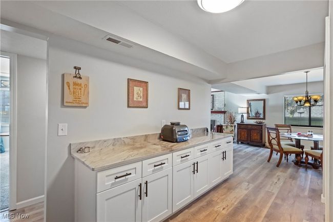 Bar featuring light wood finished floors, visible vents, a chandelier, and plenty of natural light | Image 5