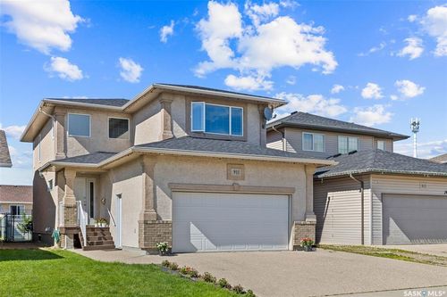 Stucco exterior with brick accents, attached garage, concrete driveway, and a manicured front lawn | Card Image