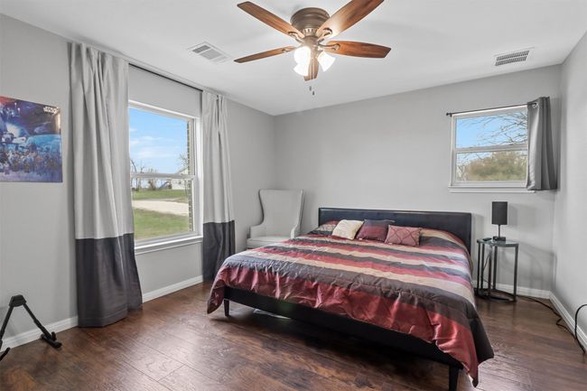 Bedroom with baseboards, visible vents, and wood finished floors | Image 12