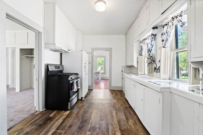 The bright white kitchen features generous cabinetry and a gas stove, perfect for home chefs. | Image 11