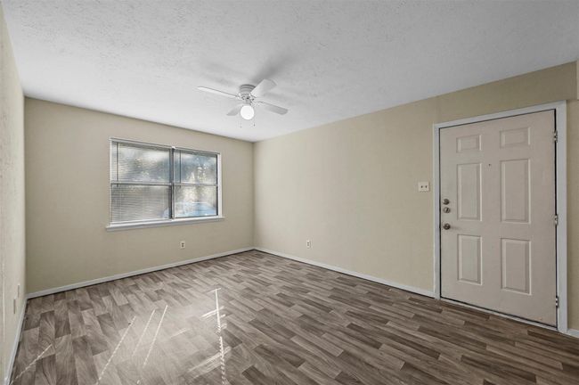 Unfurnished room with a ceiling fan, wood finished floors, and a textured ceiling | Image 9
