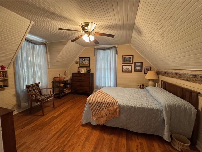 Bedroom with vaulted ceiling, wooden ceiling, wood finished floors, wood walls, and a ceiling fan | Image 26