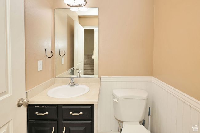 Half bath featuring toilet, a wainscoted wall, and vanity | Image 7
