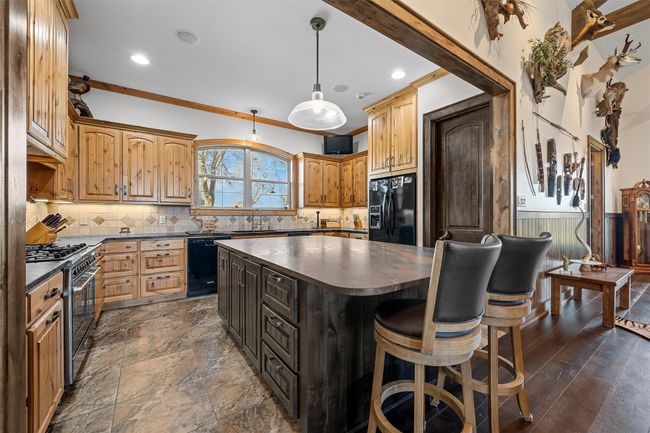 Kitchen with dark countertops, black appliances, a kitchen island, backsplash, and recessed lighting | Image 7