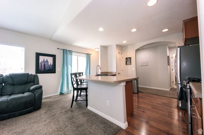 Kitchen with arched walkways, open floor plan, recessed lighting, a breakfast bar, and appliances with stainless steel finishes and LVT floors | Image 9
